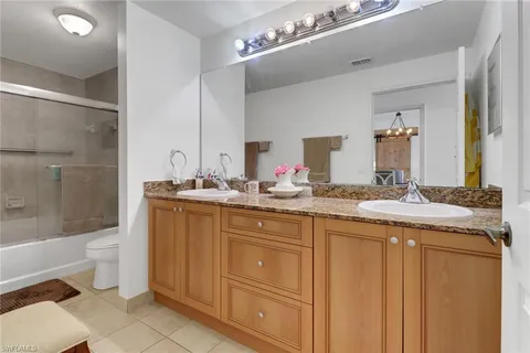a bathroom with a granite countertop sink a toilet a mirror and bathtub