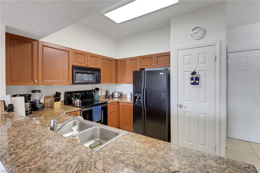 20230 Estero Gardens Circle, Unit 105 Estero, FL 33928 - Photo 6 of 44 a kitchen with stainless steel appliances granite countertop a refrigerator stove and a sink