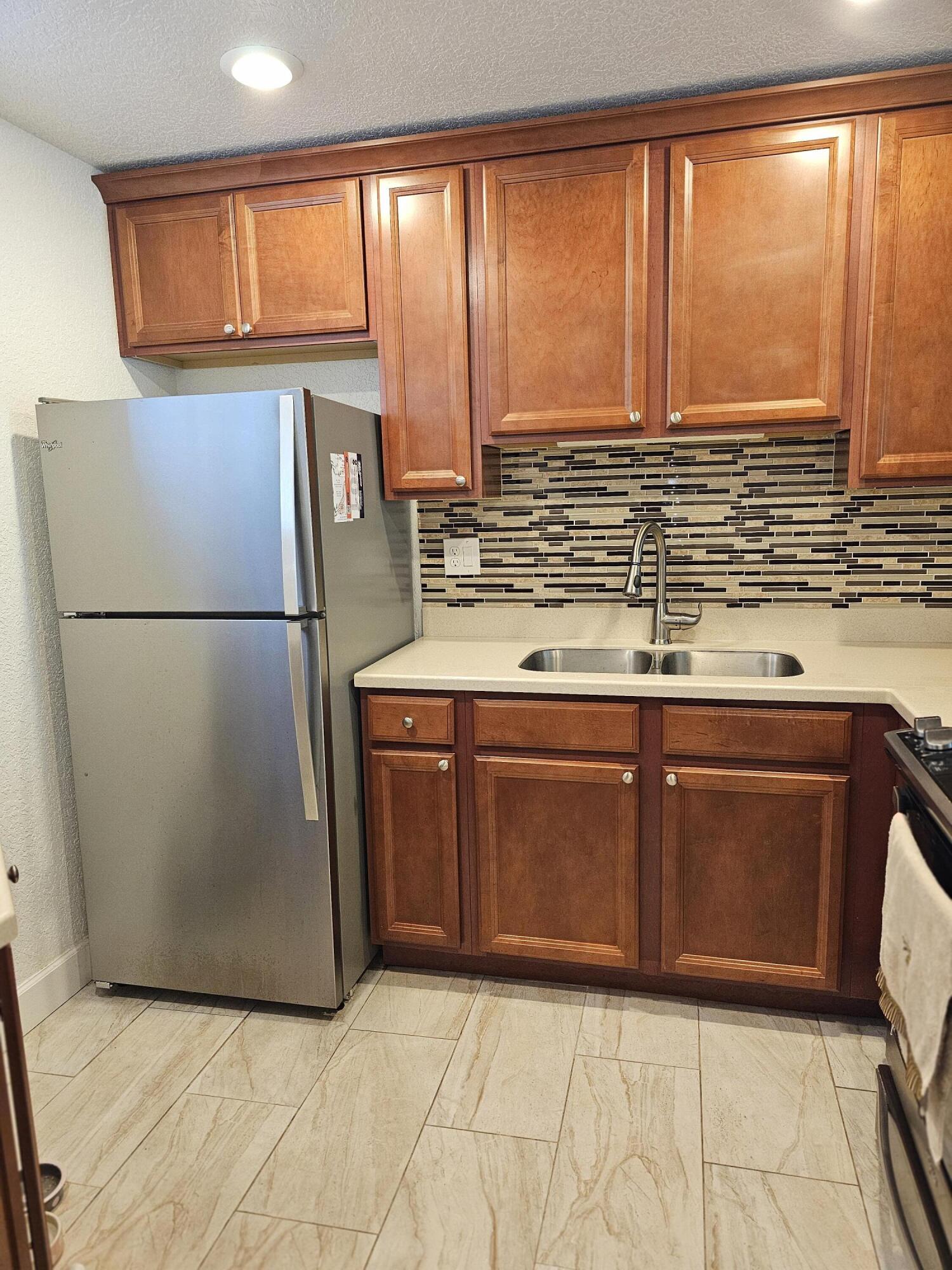 a kitchen with stainless steel appliances granite countertop a refrigerator a sink and a more cabinets