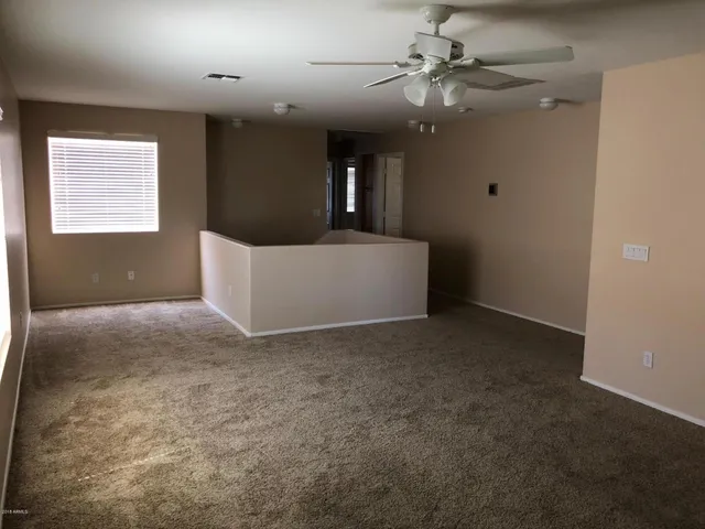 a view of an empty room with a chandelier fan