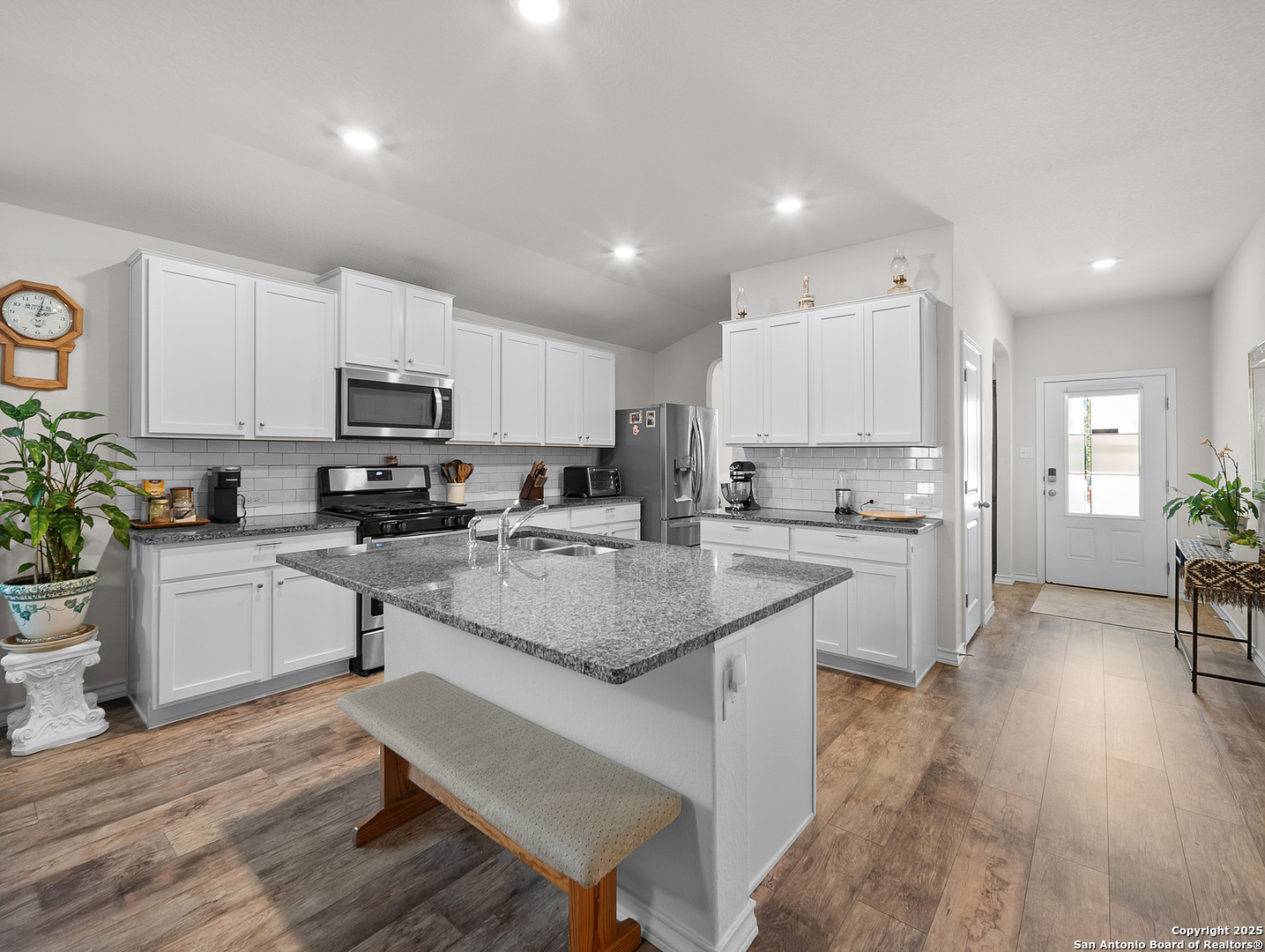 5022 Dancing Gopher San Antonio, TX 78261 - Photo 2 of 36 a kitchen with kitchen island granite countertop wooden floors white cabinets and appliances