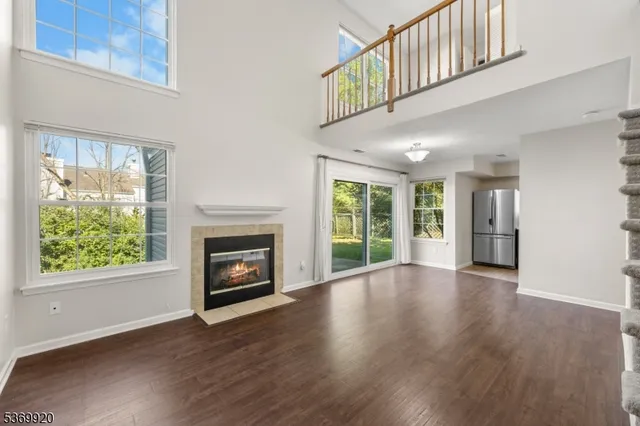 a view of an empty room with wooden floor fireplace and a window