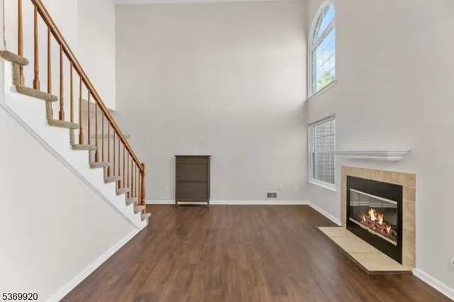 a view of an empty room with wooden floor fireplace and a window
