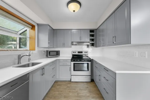 a kitchen with granite countertop a sink stainless steel appliances and cabinets