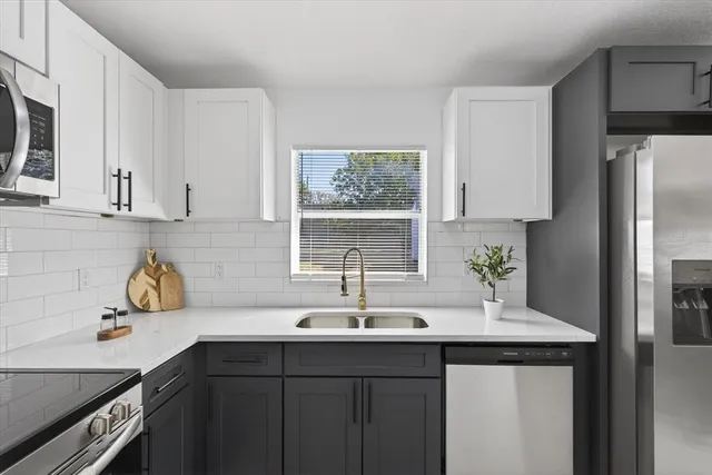 a kitchen with stainless steel appliances a sink a window and cabinets