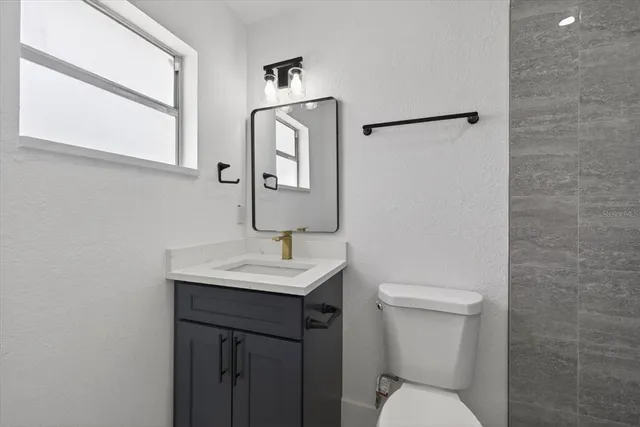 a bathroom with a toilet sink vanity and mirror