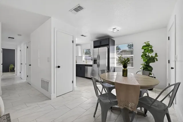 a kitchen with stainless steel appliances a dining table chairs and refrigerator