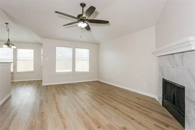 an empty room with wooden floor fan and windows