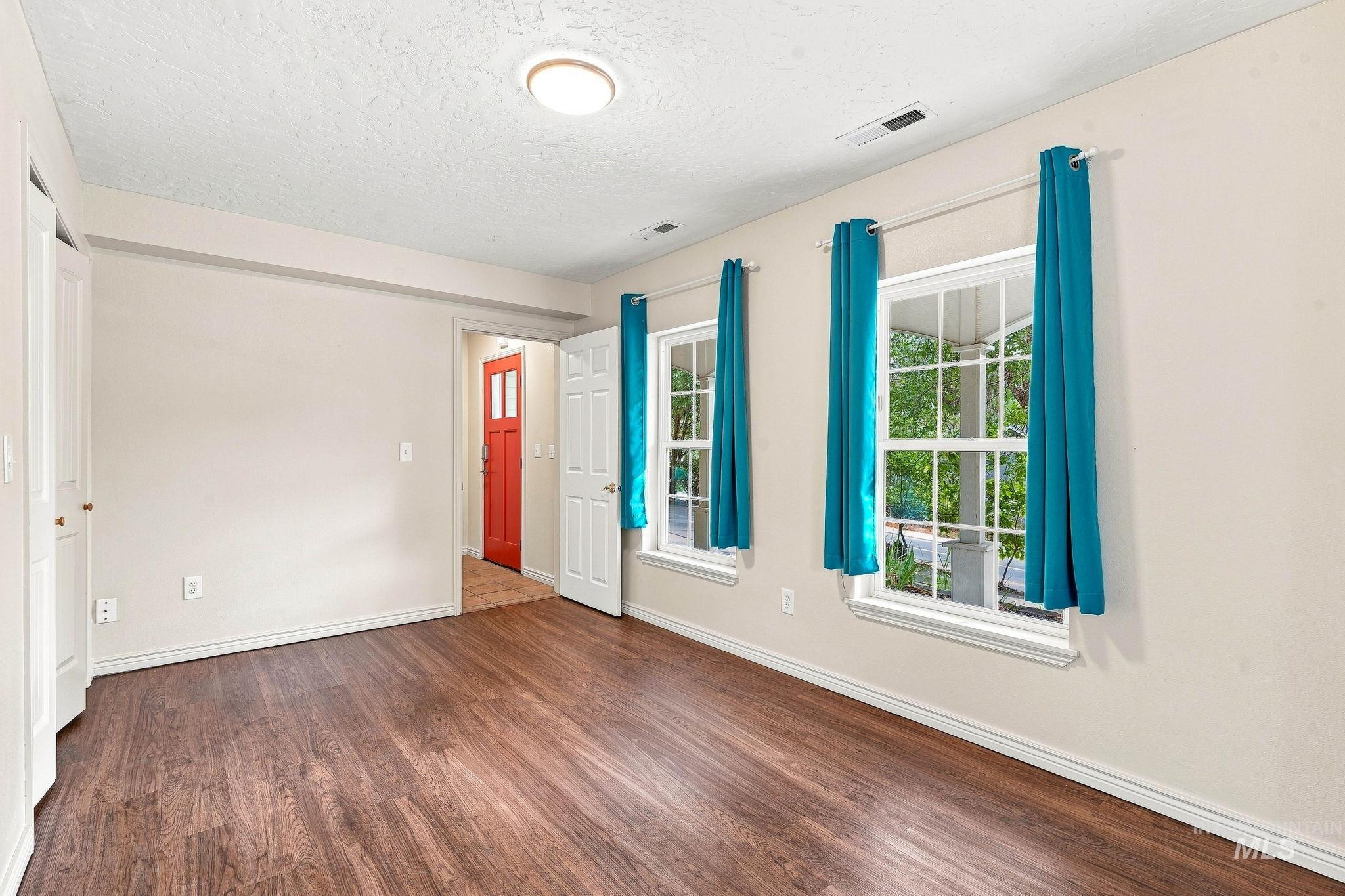 2442 West Hill Road Boise, ID 83702 - Photo 29 of 48 Wood-finish flooring, two large windows with muntins, white trim throughout, bright red door, and recessed lighting
