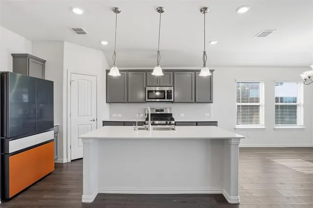 a kitchen with kitchen island a large counter top appliances and cabinets