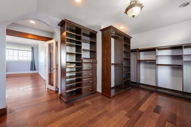 an empty room with wooden floor closet and windows