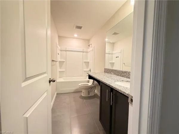 a bathroom with a granite countertop sink a toilet a mirror and shower