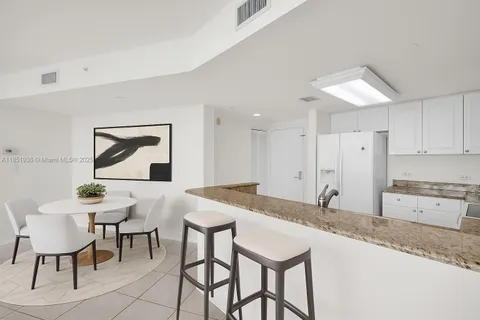 a kitchen with granite countertop a table chairs stove and white cabinets