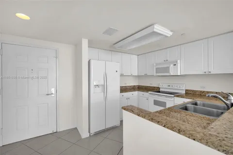 a kitchen that has a refrigerator a sink and white cabinets
