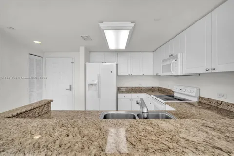 a kitchen with a refrigerator sink and cabinets