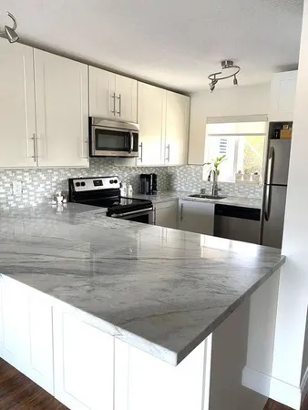a view of a kitchen with kitchen island a sink wooden floor and counter top space