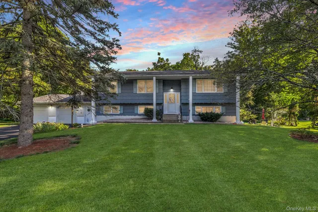 a view of a brick house with a big yard and large trees