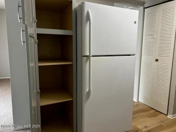 a white refrigerator freezer and a wooden floor