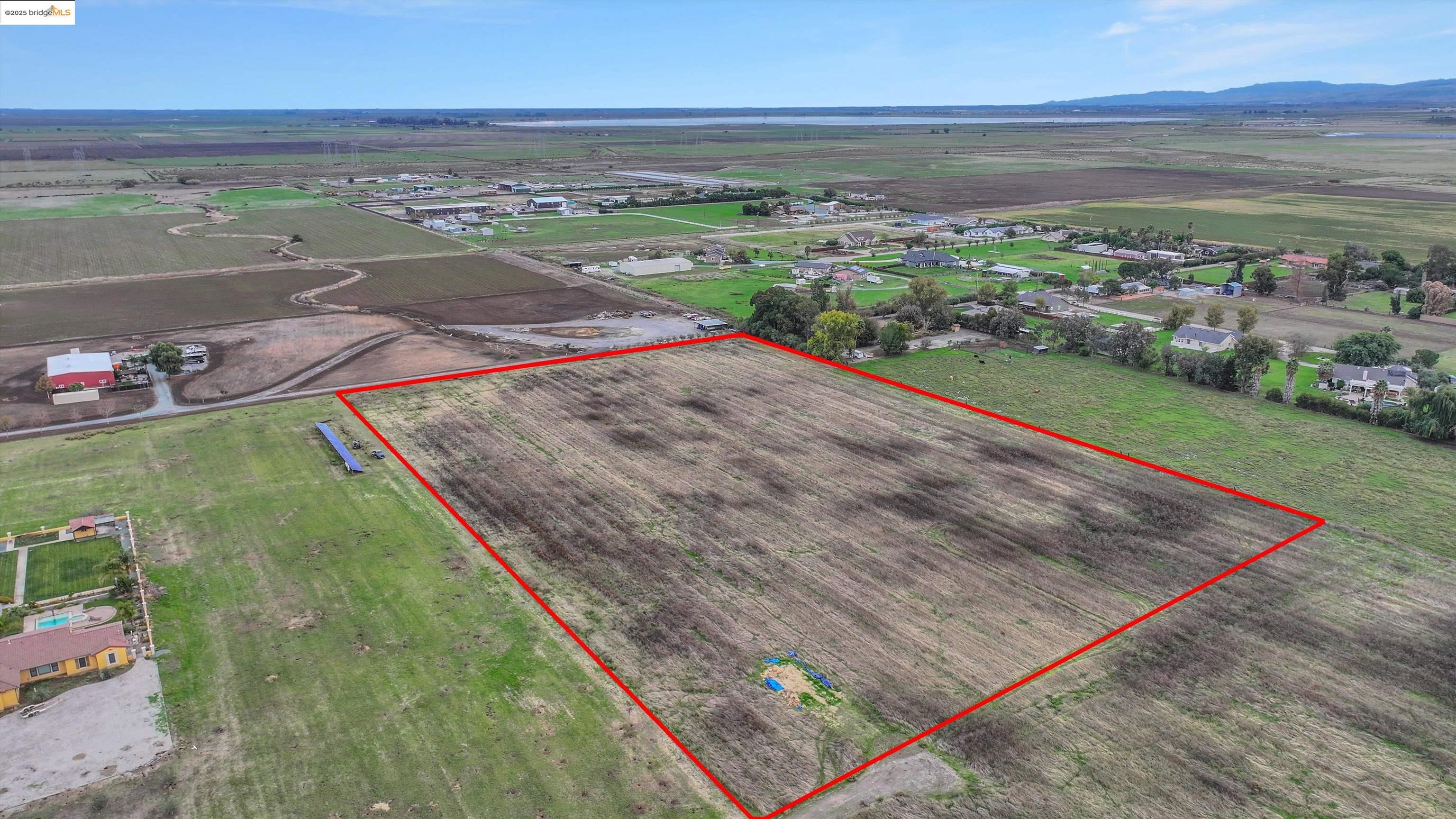 3590 Byer Road Byron, CA 94514 - Photo 11 of 12 Aerial view of sparsely populated area featuring property boundaries highlighted and a mountain backdrop