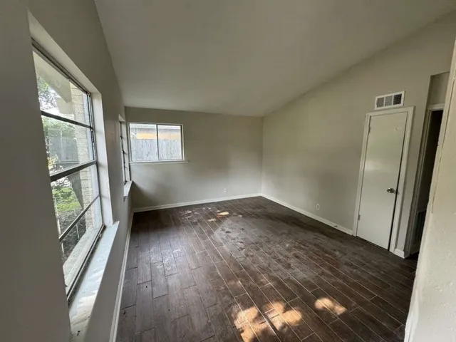 an empty room with wooden floor and windows