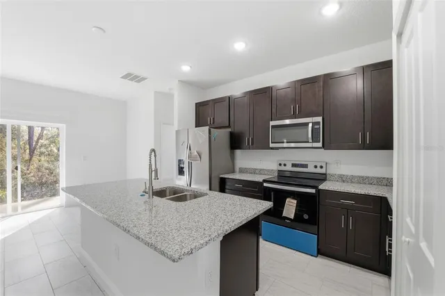 a kitchen with stainless steel appliances granite countertop a sink stove microwave and refrigerator