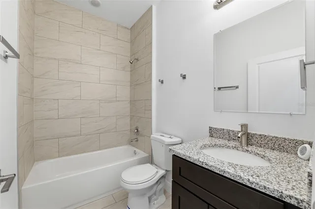 a bathroom with a granite countertop sink a toilet and bathtub