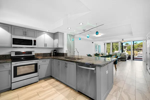 a view of kitchen with stainless steel appliances granite countertop a sink stove and refrigerator