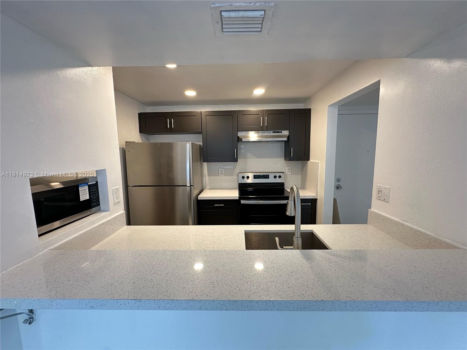 7125 Northwest 186th Street, Unit B311 Hialeah, FL 33015 - Photo 3 of 25 a kitchen with stainless steel appliances a refrigerator and a stove