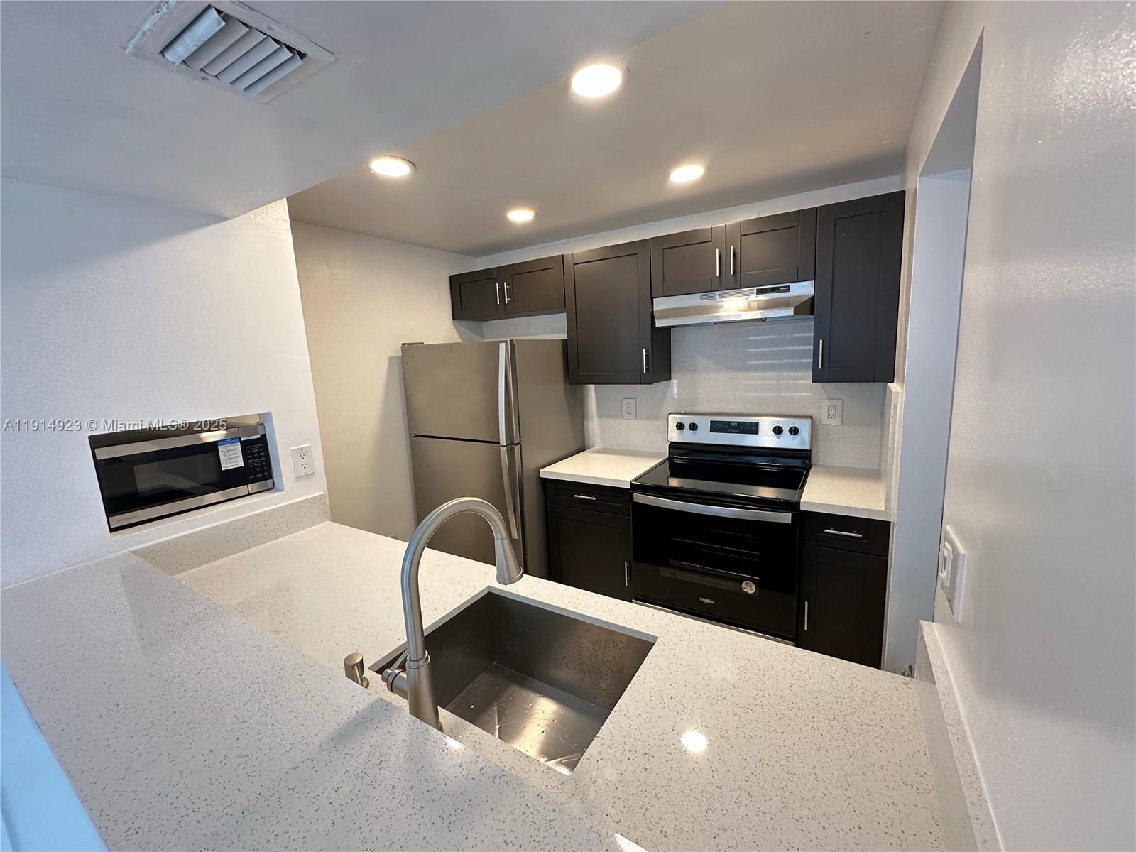 7125 Northwest 186th Street, Unit B311 Hialeah, FL 33015 - Photo 5 of 25 a kitchen with a refrigerator and a stove top oven with wooden floor