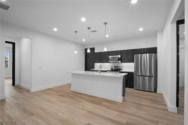 a kitchen with stainless steel appliances a refrigerator stove and wooden floor