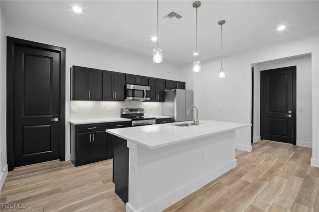 a kitchen with kitchen island a sink stainless steel appliances and cabinets