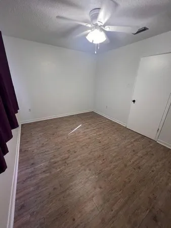 an empty room with a chandelier fan and windows