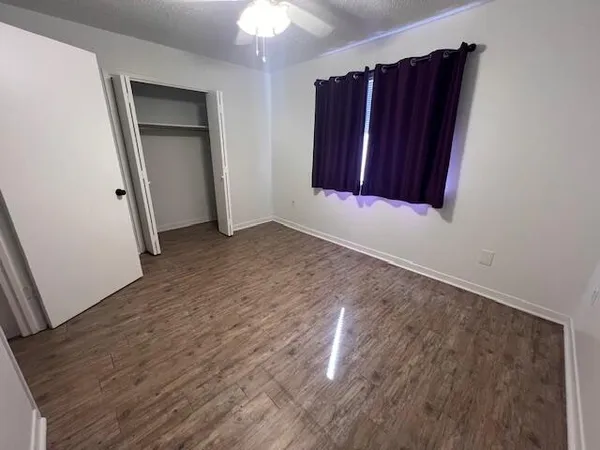 an empty room with wooden floor closet and entryway