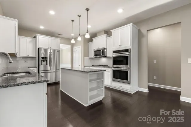 a kitchen with stainless steel appliances granite countertop a refrigerator a oven a sink and a stove