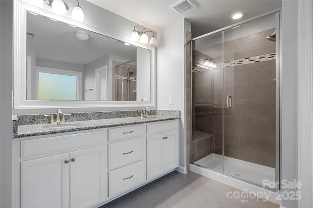 a bathroom with a granite countertop sink a mirror a shower and a mirror