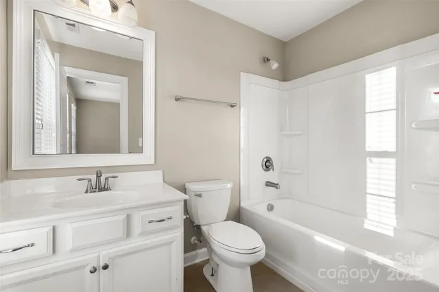 a bathroom with a toilet a sink a mirror a bathtub and vanity