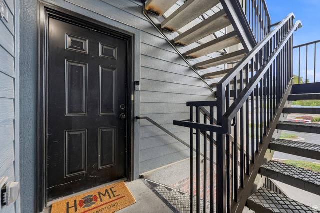 116 East Resaca Drive, Unit F6 Sandy, UT 84070 - Photo 26 of 32 Exterior entry featuring a paneled black door, horizontal siding, concrete flooring, and an external metal staircase with matching railings