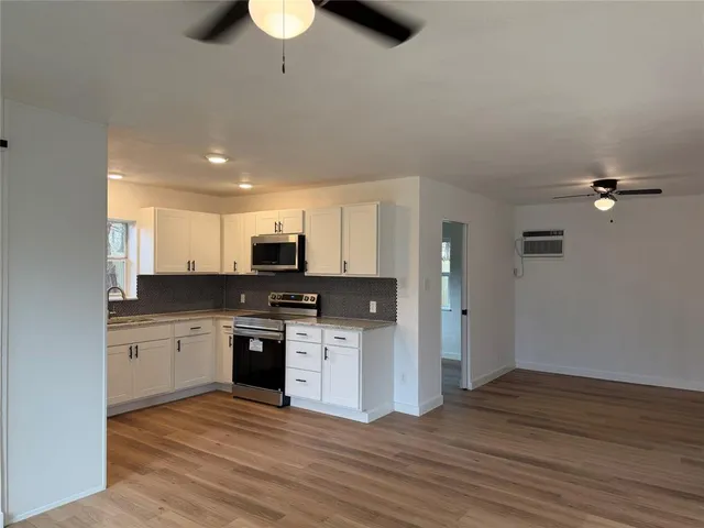 a kitchen with stainless steel appliances granite countertop a stove top oven a sink and dishwasher with wooden floor