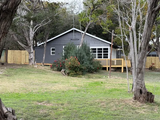 a backyard of a house with plants and large tree