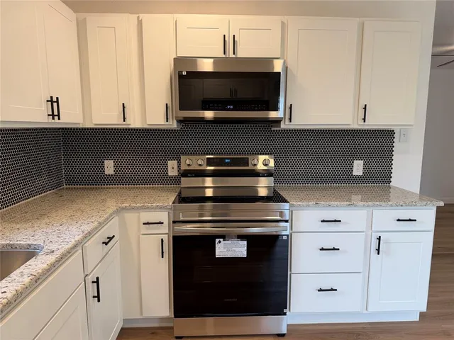 a kitchen with stainless steel appliances granite countertop a stove a microwave and oven