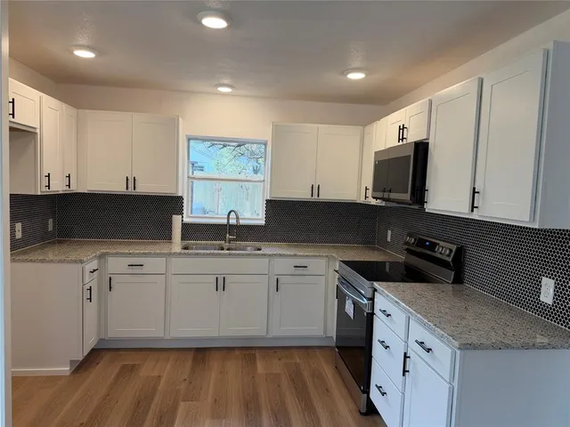 a kitchen with granite countertop a sink and white cabinets