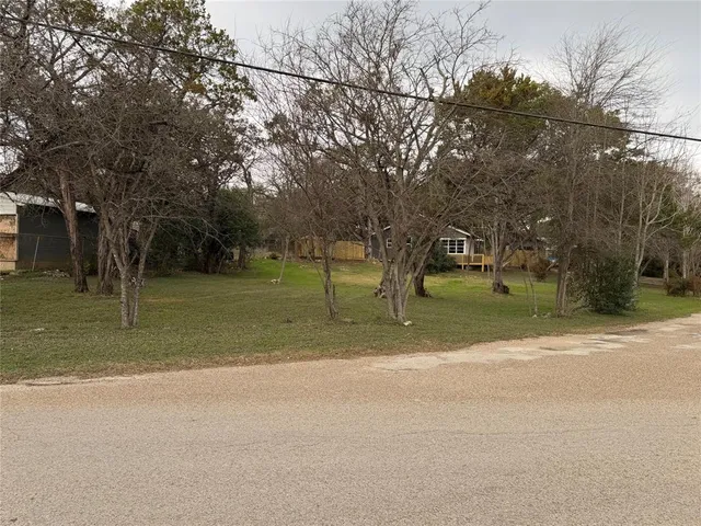 a view of a house with a big yard and large trees