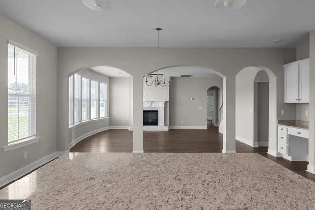 a view of an empty room with window and kitchen view