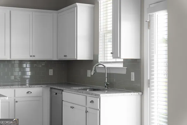 a kitchen with granite countertop white cabinets and a sink