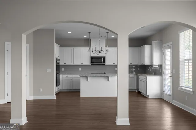 a open kitchen with white cabinets and wooden floor