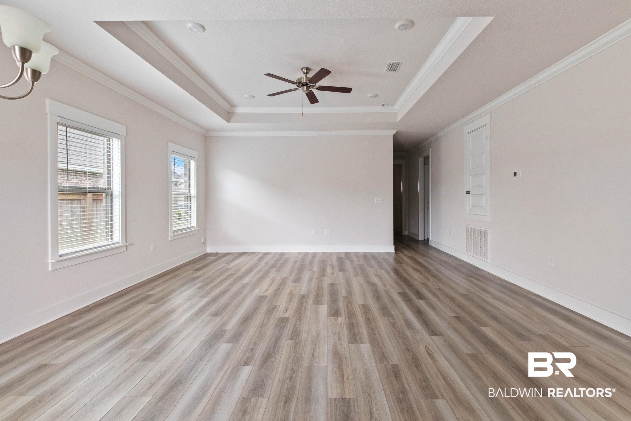 1710 Grouse Street Foley, AL 36535 - Photo 20 of 76 Spacious room featuring wood-finish flooring, a tray ceiling with a ceiling fan, and two windows with blinds