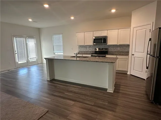an open kitchen with wooden floor and stainless steel appliances