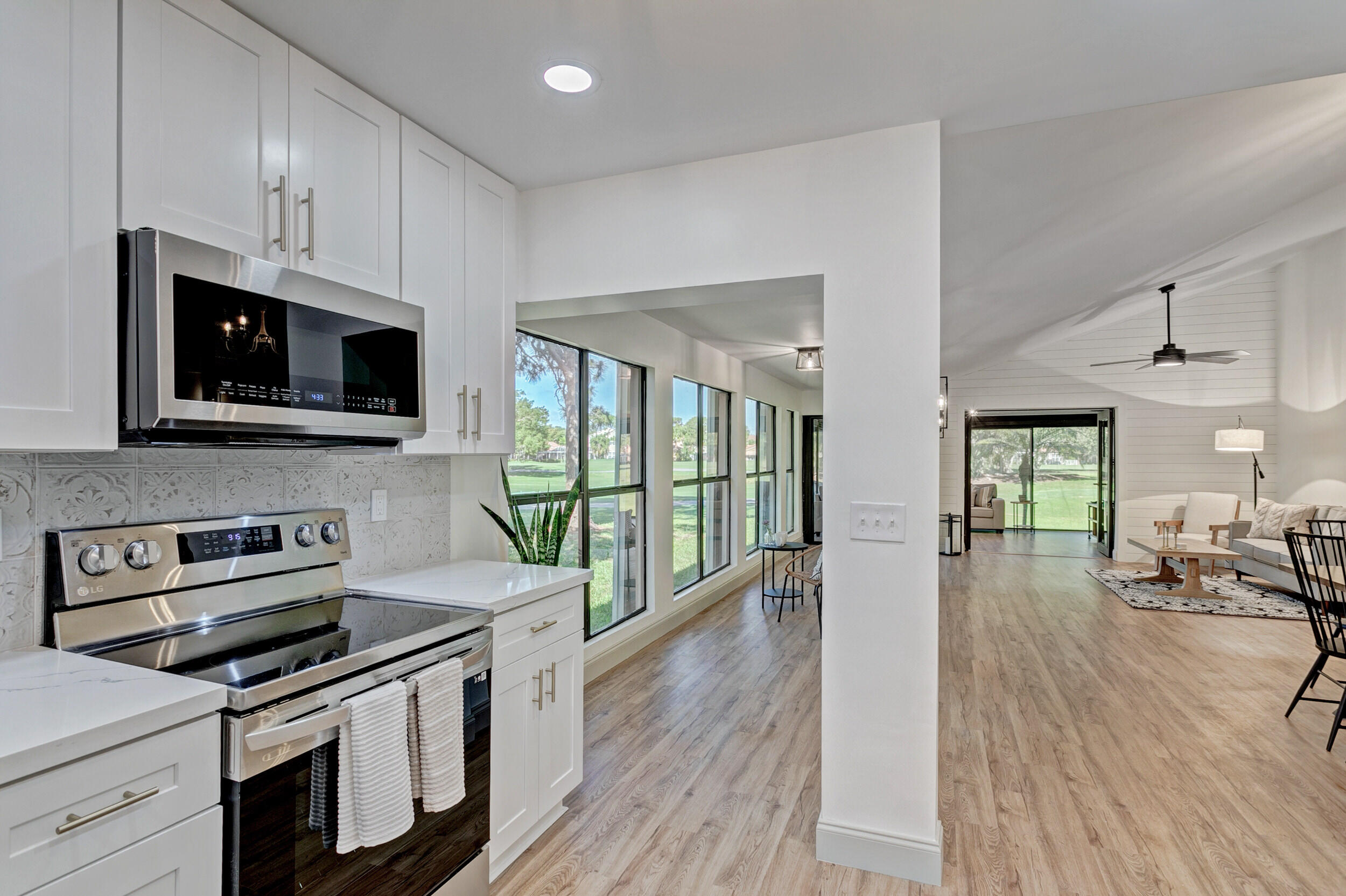24 Ironwood Way North Palm Beach Gardens, FL 33418 - Photo 20 of 74 a kitchen with stainless steel appliances a stove a sink dishwasher a microwave oven and a dining table with wooden floor