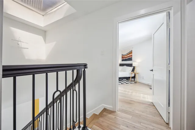 a view of a hallway with wooden floor and a bathroom