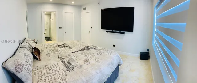 a bedroom with a bed and a flat tv screen on the dresser